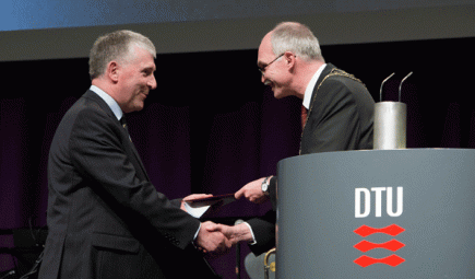 man presenting award and shaking hands with another man